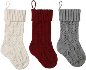 Detailed knit pattern on a set of three festive red, white, and grey Christmas stockings