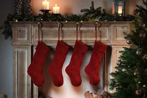 Set of four red knitted Christmas stockings hanging on a rustic wooden fireplace