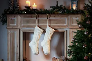 Detailed texture of ivory cable knit Christmas stocking hanging on a vintage fireplace