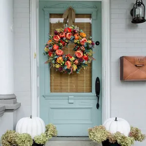 Herbstkranz mit Kürbissen und Rosen an einer blauen Vintage-Haustür im Freien