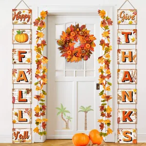 Detail of autumn maple leaf garlands and wooden festive hanging signs on a white door