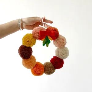 Guirnalda navideña artesanal con pompones de colores y lazo rojo para decoración festiva