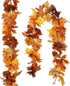 Detail of three faux maple leaf garlands with vibrant orange and red autumn color tones
