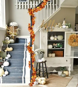 Detail of artificial autumn maple leaf garland wrapped around a dark wooden staircase