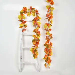 Close-up of artificial fall maple leaf garlands with realistic orange and yellow gradients