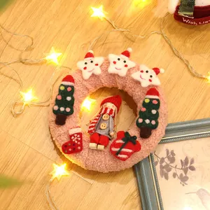 Detalle de corona navideña de felpa rosa con estrellas sonrientes y pequeños ornamentos