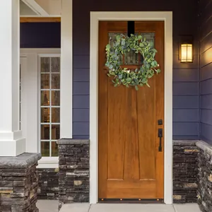 Close-up of artificial eucalyptus wreath with white flowers and a black door hook