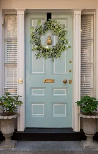 Close-up of green eucalyptus wreath with white flowers on a blue wooden door