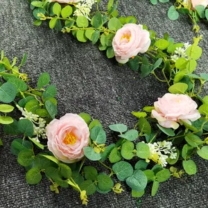Macro detail van kunstmatige camelia en eucalyptus liaan met roze rozen en zijden bladeren