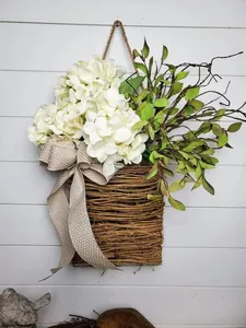 Close-up of artificial white hydrangea and green leaves in rustic rattan door basket