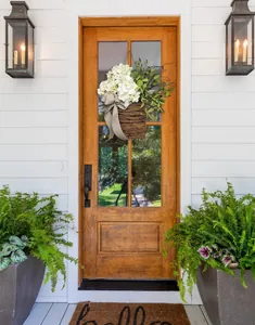 Hanging basket with white hydrangeas and green foliage on a wooden door with a bow