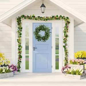 Front door display of olive leaf wreath with red berry garland on blue wooden door