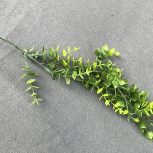 Close-up of artificial eucalyptus branch with gradient green leaves on grey surface