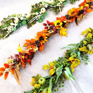 Detail of artificial autumn garland with white pumpkins, maple leaves and sunflowers