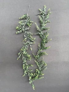 Detail of two artificial eucalyptus vines with realistic frosted green leaves on dark background