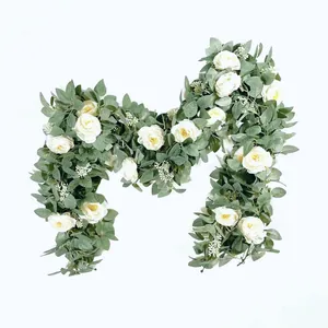 Detail van witte kunstmatige rozen en groene bladeren gerangschikt in een M-ontwerp