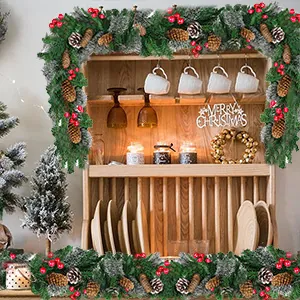 Lush 2.7m frosted Christmas garland with pine cones and red berries on a wooden cabinet