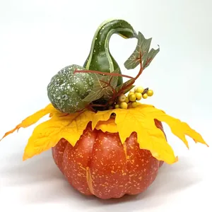 Detail of harvest pumpkin centerpiece with autumn maple leaves and small berries