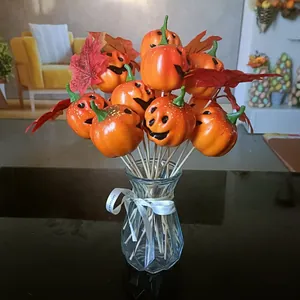 Close-up of decorative mini pumpkins with maple leaves in a glass vase for Halloween