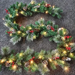 Detail of Christmas garland with frosted pine needles, red berries, cones and LED lights