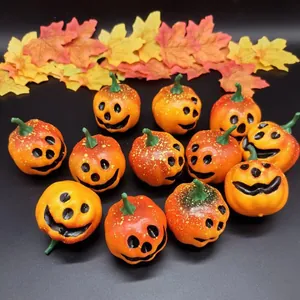 Detailed overhead shot of mini orange pumpkins with jack-o-lantern faces and maple leaves