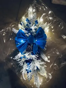 Detail of blue velvet bow and snowy pine branches with LED lights on Christmas garland
