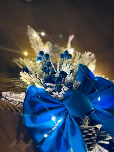 Detail of Christmas garland with blue bow, glitter berries, snow needles and LED lights