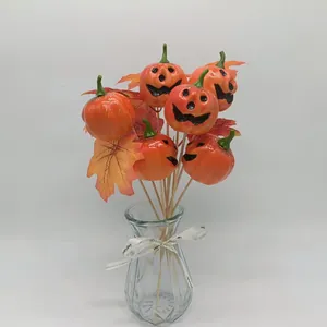 Detail of Harvest Festival faux pumpkin picks with maple leaves in a glass vase