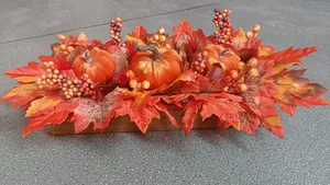 Close-up of artificial orange pumpkins and maple leaves in a rustic wooden base tray
