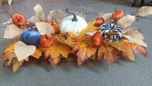 Detail of harvest pumpkin centerpieces with maple leaves on a wooden base