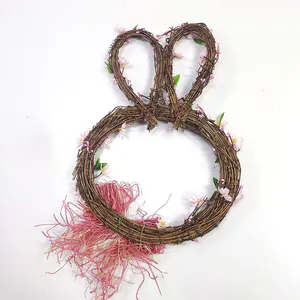 Gros plan d'une couronne de lapin en rotin avec fleurs roses et feuilles vertes