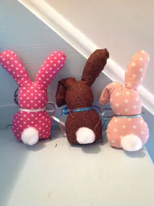 Détail de trois lapins de Pâques en tissu avec queues pompon et nœuds en ruban