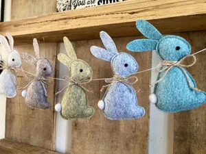 Détail de lapins de Pâques en feutre coloré avec queues à pompons sur fond de bois