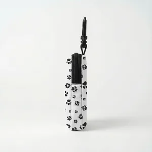 Detail of dog treat pouch showing white fabric with black paw prints and clip