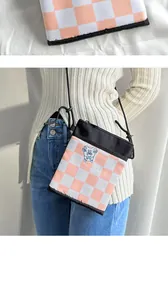 Close-up of pink checkered crossbody bag with cute blue cartoon bear embroidery detail