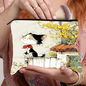 Trousse à maquillage en toile avec imprimé chat et fermeture éclair, tenue par un mannequin