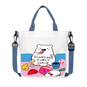 Detail of white canvas tote featuring cartoon bear print and blue adjustable shoulder strap