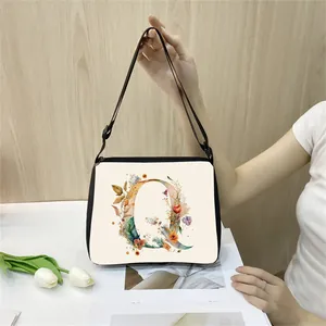 Close-up of floral letter Q print on minimalist beige canvas tote bag with black strap