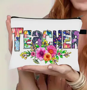 Detail van witte canvas make-uptas met bloemige Teacher-opdruk en zwarte rits