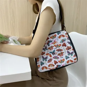 Detailed view of white tote bag with colorful butterfly prints and black shoulder strap