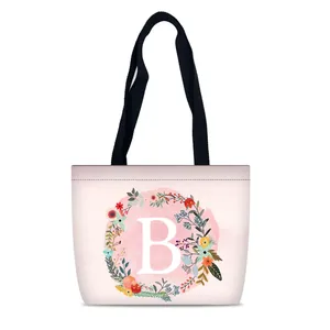 Pink canvas tote bag with letter B floral print and black handles for travel