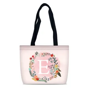 Pink canvas tote bag with floral letter E print and black handles for travel