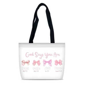 Détail des imprimés nœuds roses et des citations inspirantes sur le sac cabas blanc en toile