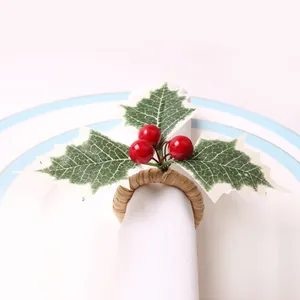 Close-up of Christmas napkin ring with green holly leaves, red berries and woven band