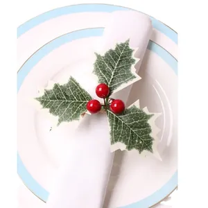 Christmas napkin ring with green holly leaves and red berries on a white fabric napkin