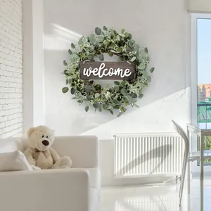 Corona de eucalipto con cartel de bienvenida de madera en la pared de una sala moderna