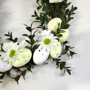Ghirlanda pasquale con uova maculate, margherite bianche e foglie verdi su bianco