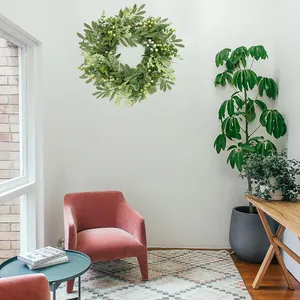 Couronne d'eucalyptus artificielle moderne avec baies vertes sur un mur blanc de salon
