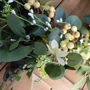 Large eucalyptus leaf wreath with yellow berries and white buds on a rustic wooden background