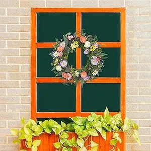 Détail d'une couronne de fleurs sauvages artificielles sur une fenêtre en bois orange rustique